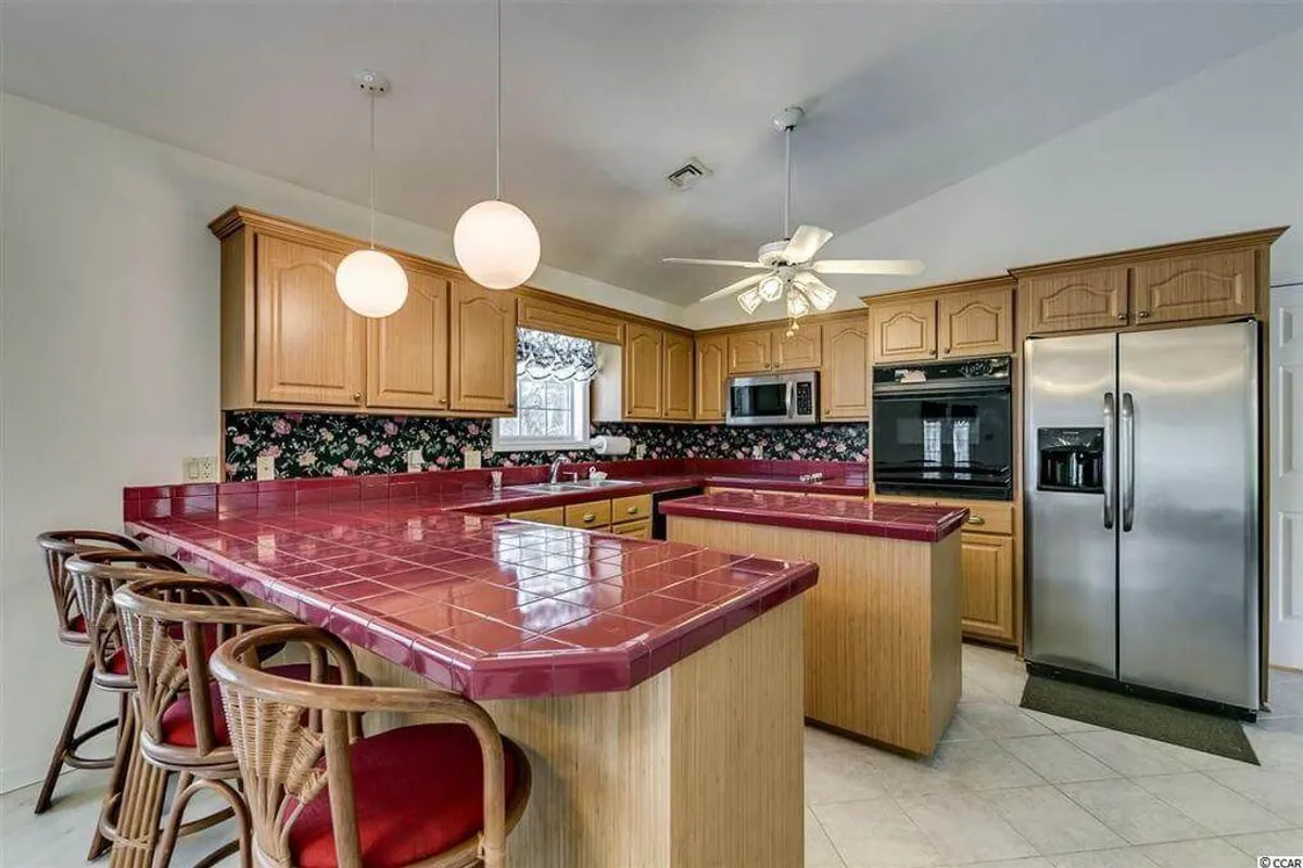 A bright, welcoming kitchen features a spacious island, modern cabinetry, and visible appliances, creating a perfect spot for both meal prep and casual gatherings. The open layout suggests easy interaction between the kitchen, dining, and living areas.